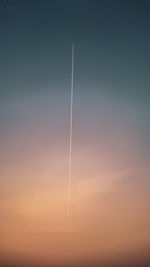 Low angle view of vapor trails against sky during sunset