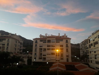 Exterior of illuminated buildings in town against sky at sunset
