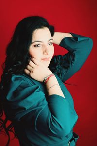 Portrait of young woman standing against yellow background