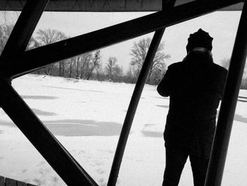 Silhouette man standing by snow against sky during winter