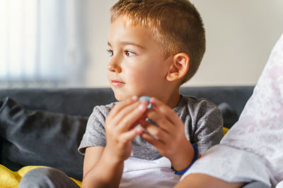 Boy looking away while sitting on sofa at home