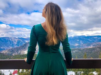 Rear view of woman standing in balcony against mountains