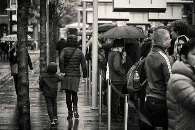 Rear view of people walking on street in city