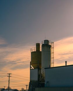 Low angle view of factory against sky during sunset