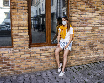 Full length of woman standing against brick wall