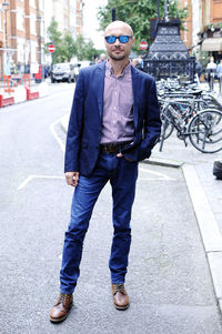 Portrait of businessman standing on road in city