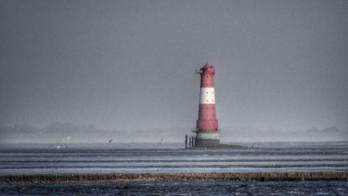 Lighthouse by sea against sky