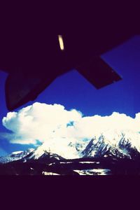 Snow covered mountain range against cloudy sky