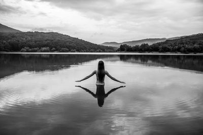 Rear view of woman in lake against sky