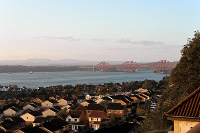 High angle view of city by sea and a bridge against sky