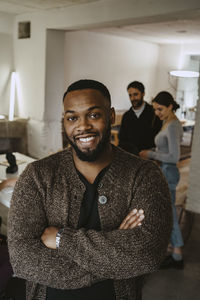 Smiling young male professional with arms crossed in creative office