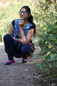 Portrait of young woman crouching on land outdoors