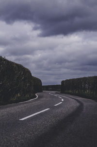 High angle view of road amidst hedge against cloudy sky