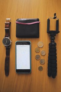 Directly above shot of mobile phone and coins with personal accessories on table