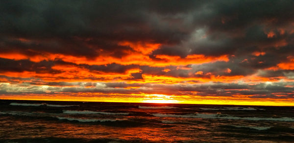 Scenic view of sea against dramatic sky during sunset