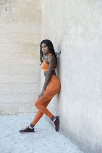 Full length of woman leaning against wall