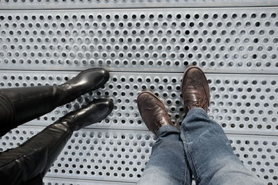 Low section of man and woman standing on metallic floor