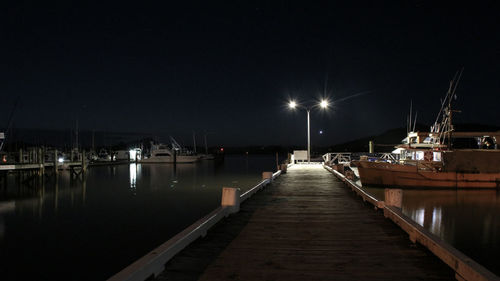 Illuminated pier in harbor on lake at night