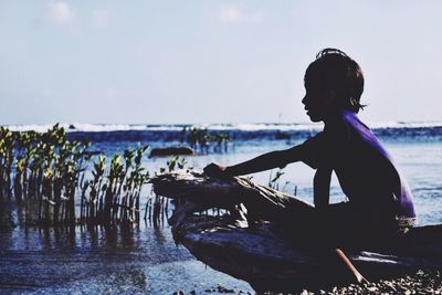 Child sitting on a driftwood