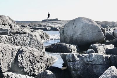 Rear view of person on rock against sky