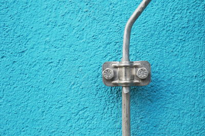 Close-up of telephone pole against blue wall