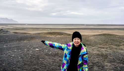 Portrait of smiling woman gesturing while standing on land during winter