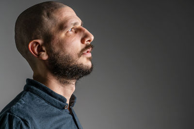 Portrait of young man looking away against black background