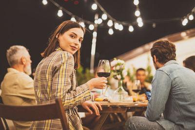 Portrait of young woman using mobile phone while sitting at restaurant