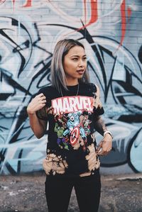 Young woman standing against graffiti wall