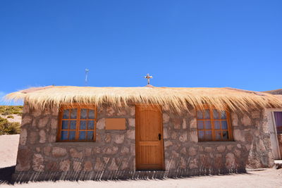 Bird on built structure against clear blue sky