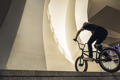 Shadow of man on bicycle by building