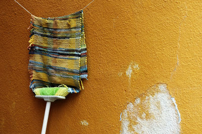 Doormat hanging on clothesline against yellow wall