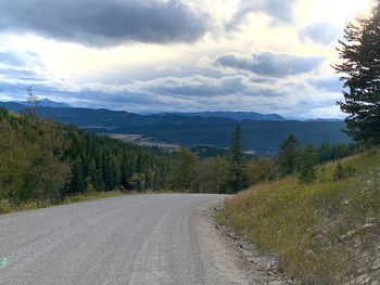 Scenic view of road by mountains against sky