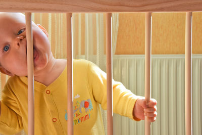 Portrait of baby boy looking through crib