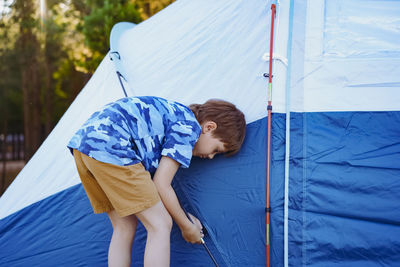 Cute little caucasian boy helping to put up a tent. family camping concept