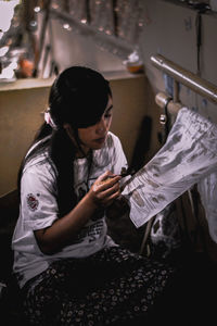 Young woman holding camera while standing in kitchen