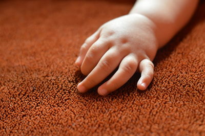 Cropped hand of baby boy on carpet