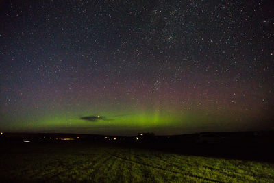 Scenic view of illuminated field against sky at night