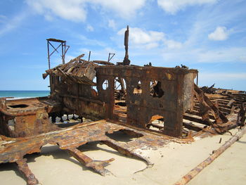 Old rusty ship at sea shore against sky