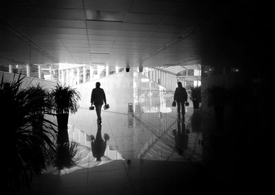 Silhouette people walking in illuminated underground walkway