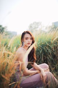 Portrait of young woman sitting on grassy land