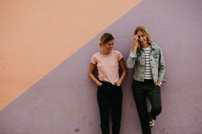 Young woman standing against wall