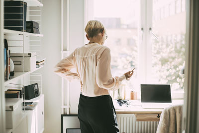 Rear view of woman in office at home talking on the phone