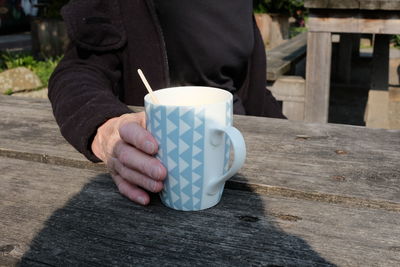 Midsection of man holding coffee cup