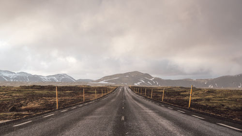 Empty road along landscape against sky