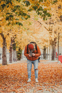 Full length of woman standing by autumn leaves