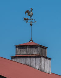 Low angle view of weather vane against blue sky