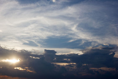 Low angle view of sunlight streaming through clouds