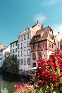 View of buildings by houses against sky