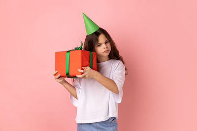 Midsection of woman holding gift against pink background